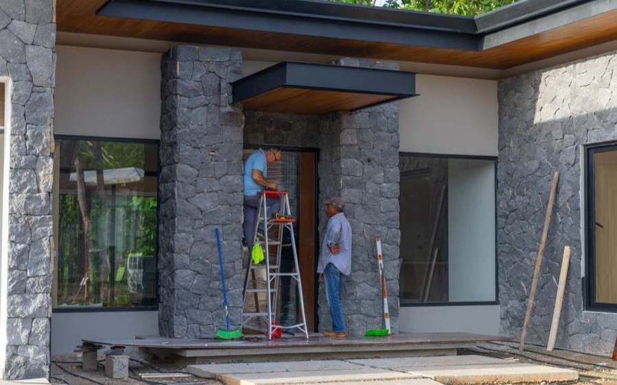 Crew at work on the volcanic-stone entry of a Black Coast home